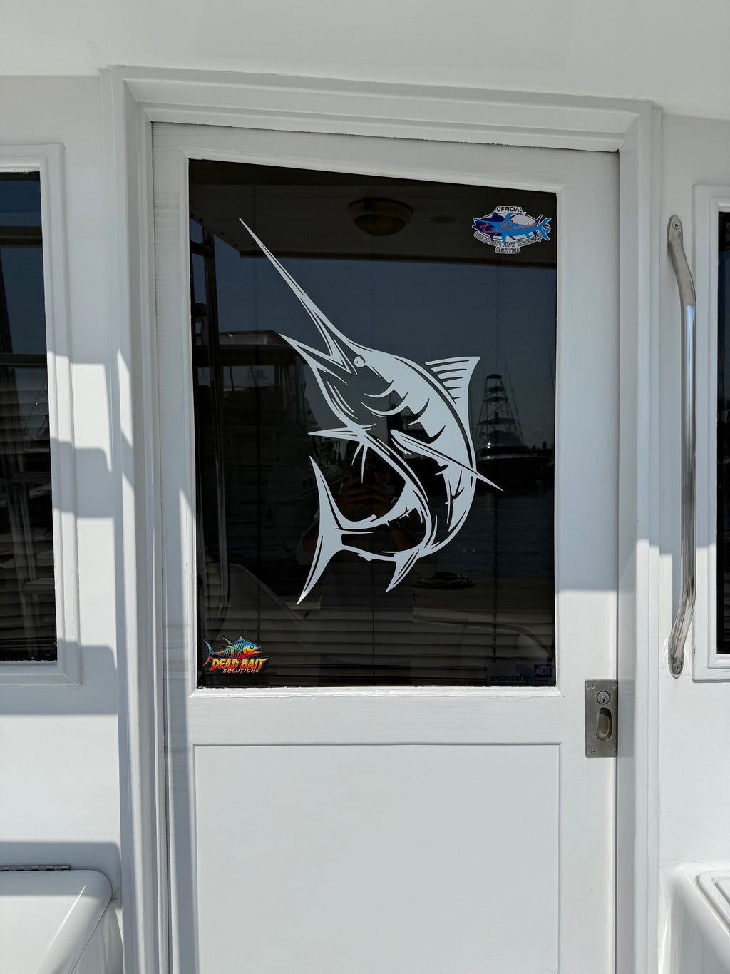 Glass door with a fish design and Meguiar's logo on a vehicle